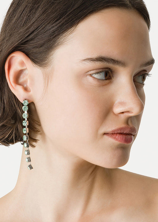 Close-up of a woman wearing a dangling earring with a neutral background