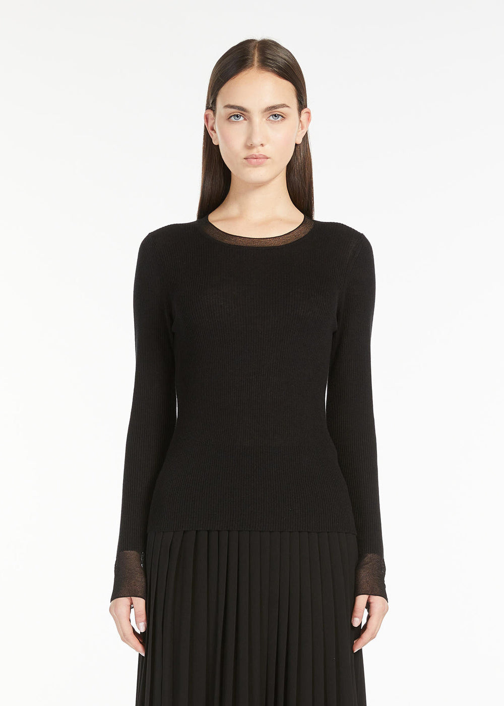 Woman wearing a black long-sleeve top and skirt on a white background