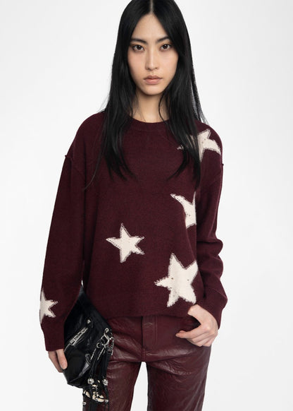 Woman wearing a burgundy sweater with star patterns on a white background