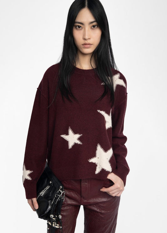 Woman wearing a burgundy sweater with star patterns on a white background