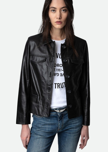 Person wearing a black leather jacket over a white graphic t-shirt and blue jeans on a light gray background