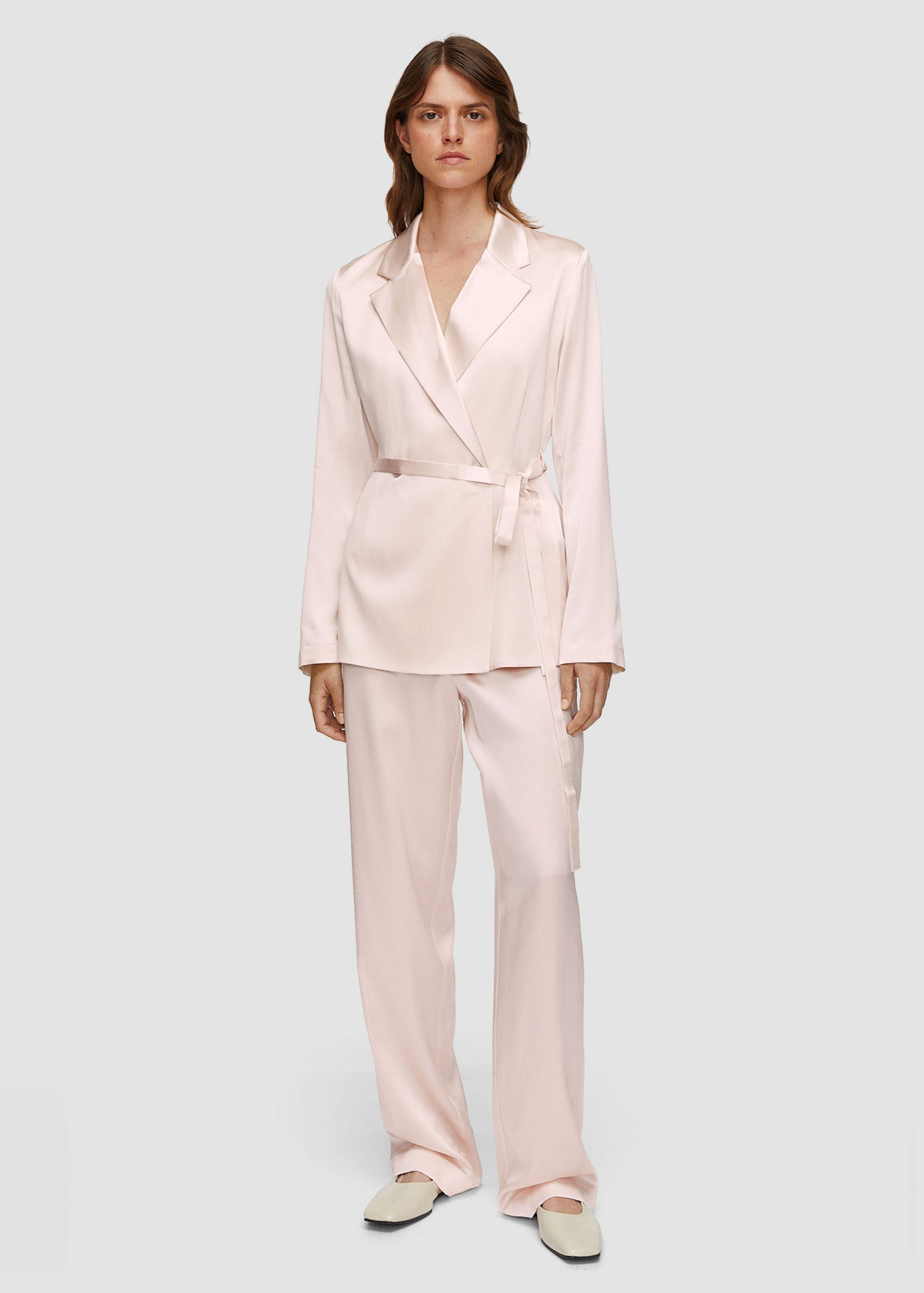 Woman wearing a light pink suit on a white background