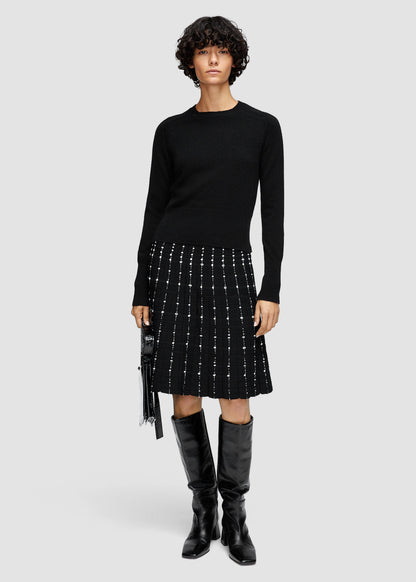 Person wearing a black long-sleeve top and black skirt with white pattern on a light gray background