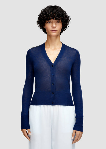 Woman wearing a blue cardigan over a white top on a light gray background