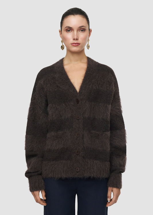 Woman wearing a brown cardigan against a plain background