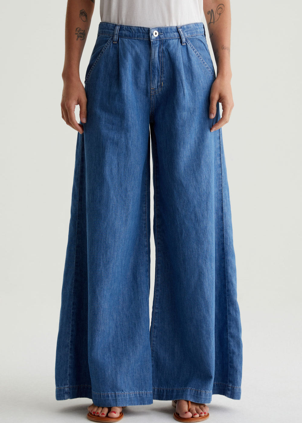 Person wearing blue wide-leg jeans on a plain background