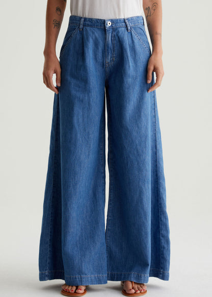 Person wearing blue wide-leg jeans on a plain background