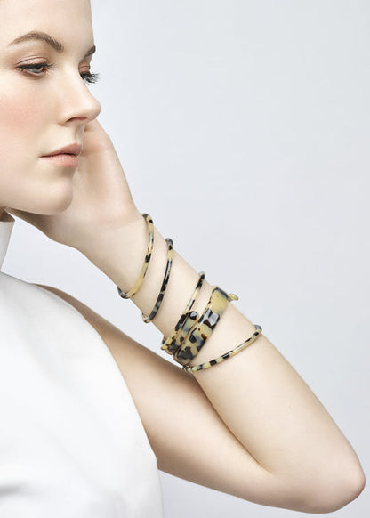 Woman wearing multiple bracelets on her wrist against a plain background