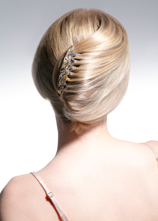 Blonde hair bun with decorative hair clip on a plain background
