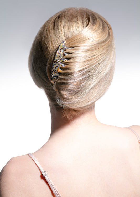 Blonde hair bun with decorative hair clip on a plain background