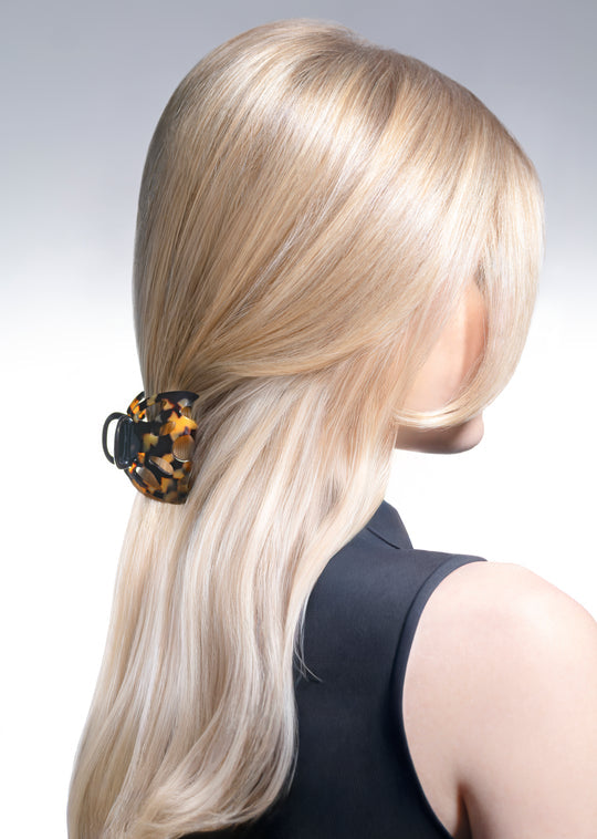 Person with long blonde hair wearing a leopard print scrunchie on a gray background