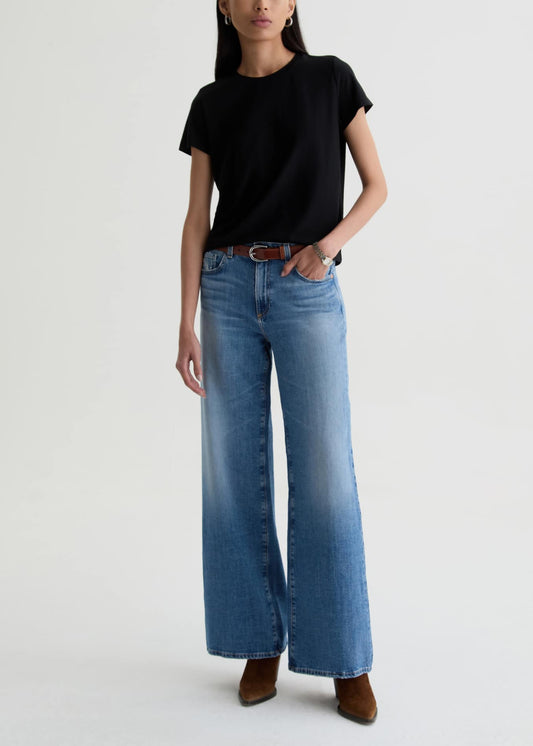 Person wearing a black t-shirt and blue jeans on a white background