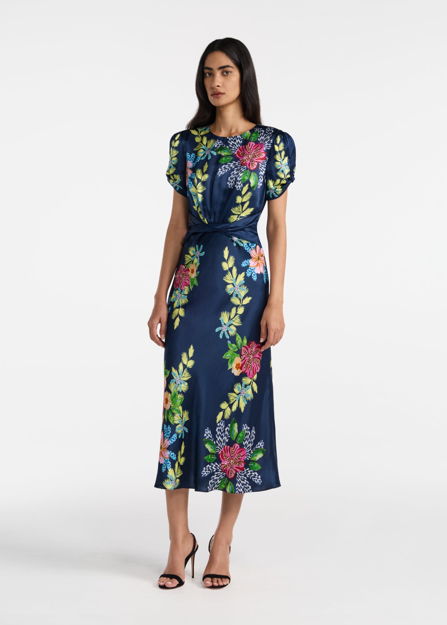 Woman wearing a navy dress with colorful floral patterns on a white background