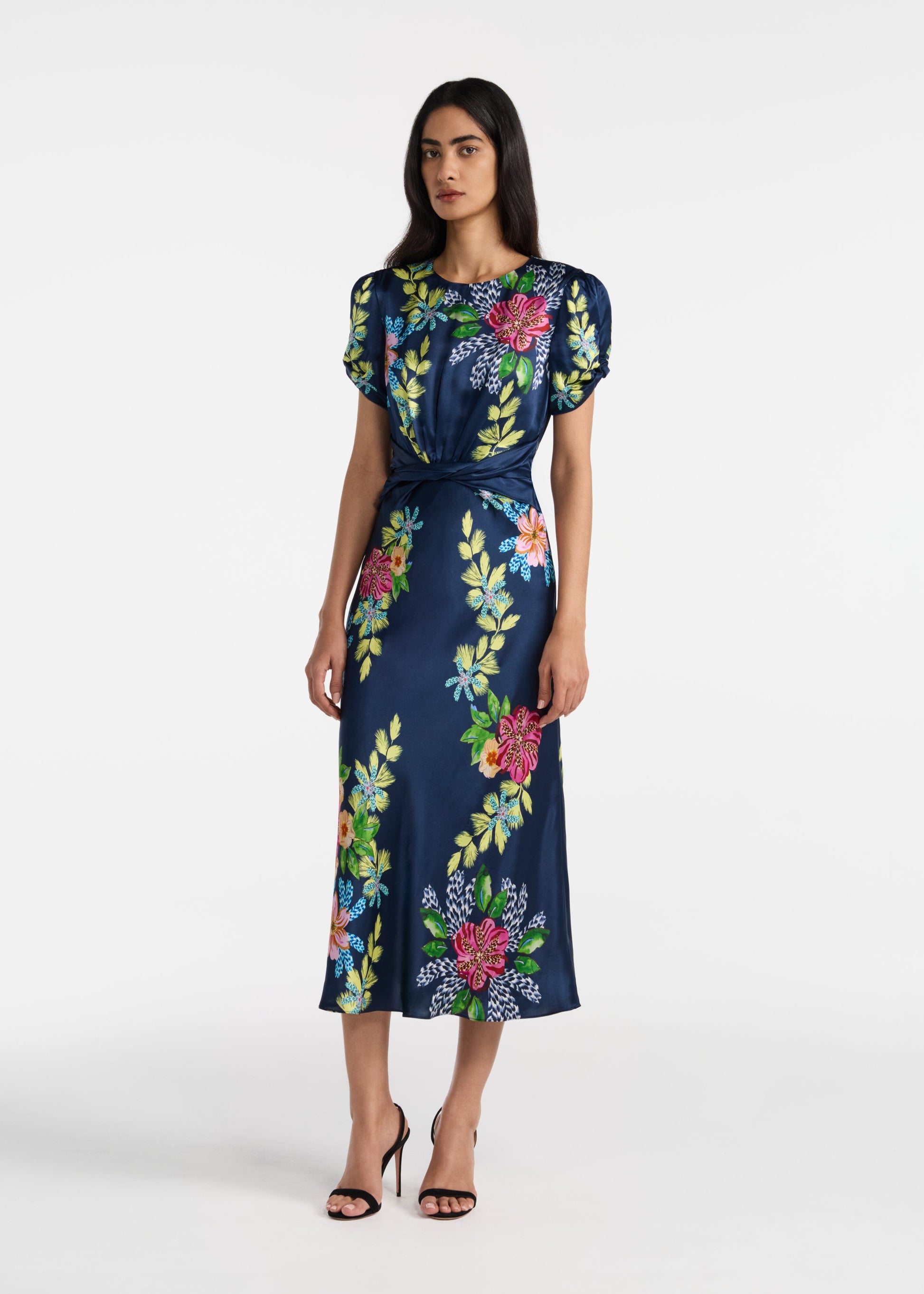 Woman wearing a navy dress with colorful floral patterns on a white background