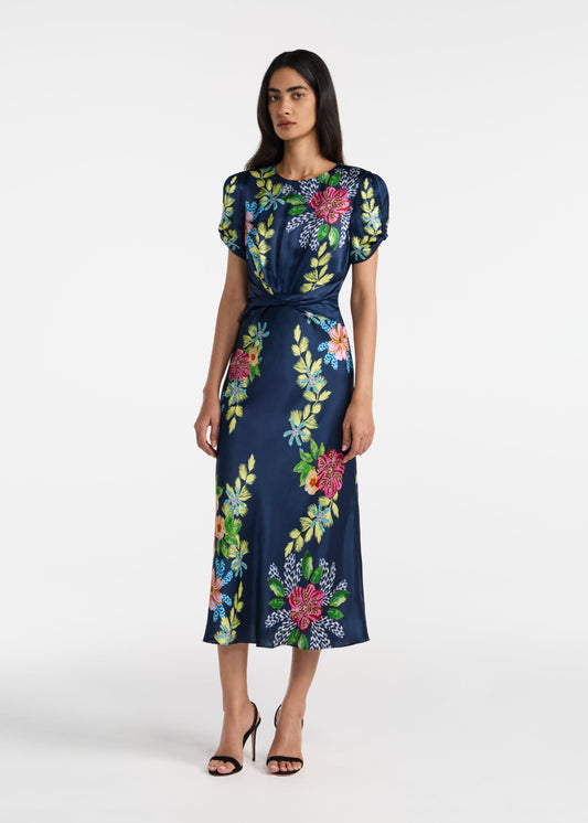 Woman wearing a navy dress with colorful floral patterns on a white background