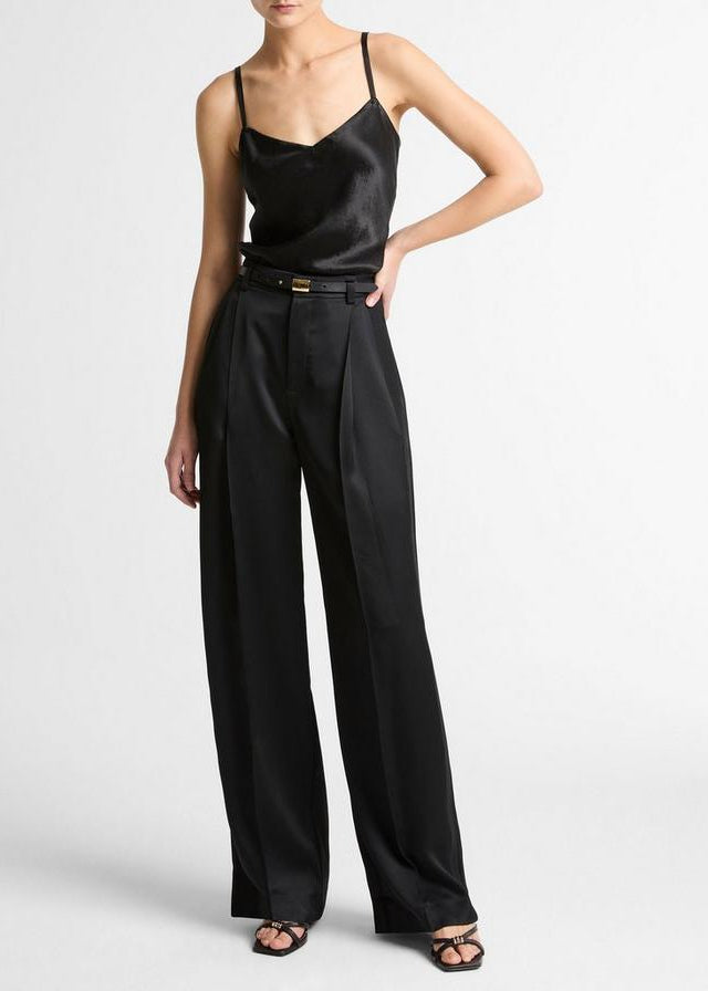 Person wearing a black satin top and wide-leg pants on a white background