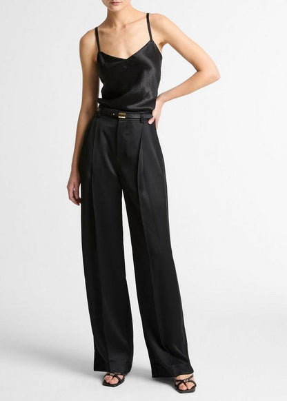 Person wearing a black satin top and wide-leg pants on a white background