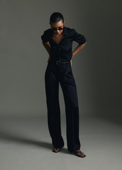 Person wearing a black outfit against a gray background