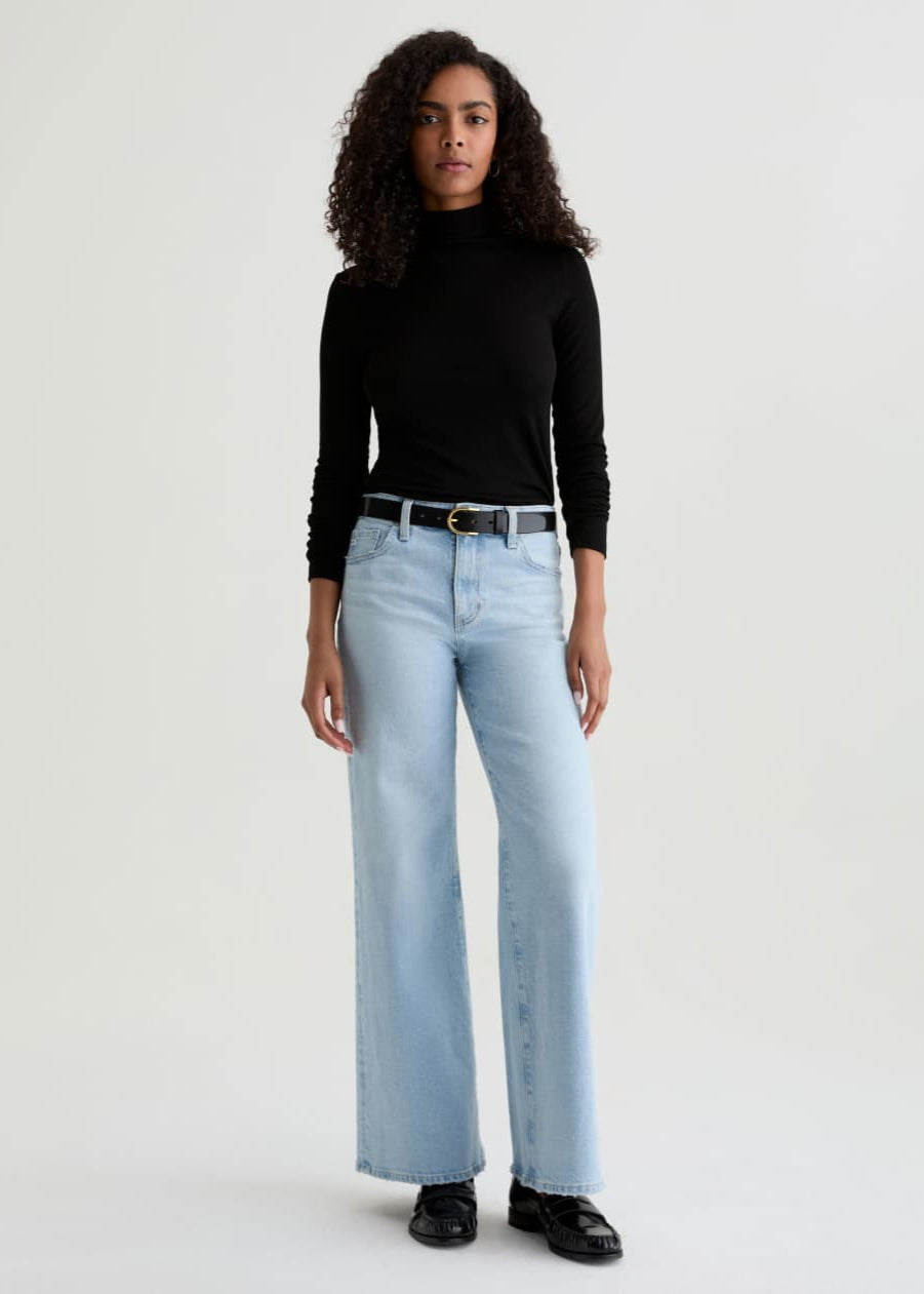 Person wearing light blue jeans and a black top on a white background