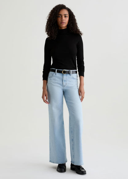 Person wearing light blue jeans and a black top on a white background