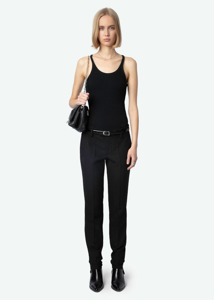 Woman wearing a black tank top and pants with a black handbag on a white background