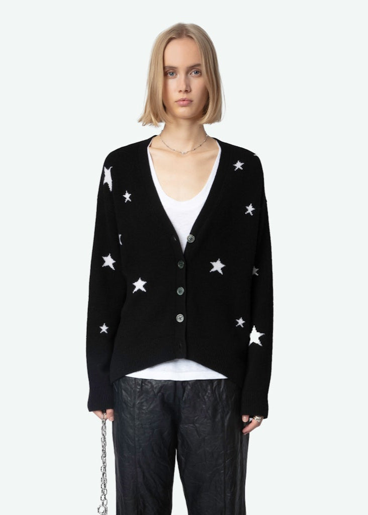 Person wearing a black cardigan with white star patterns on a white background