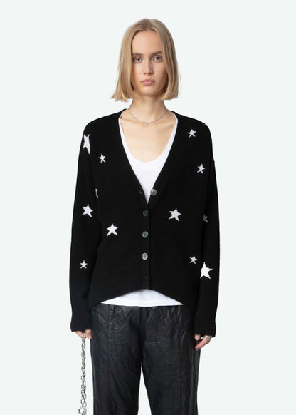 Person wearing a black cardigan with white star patterns on a white background