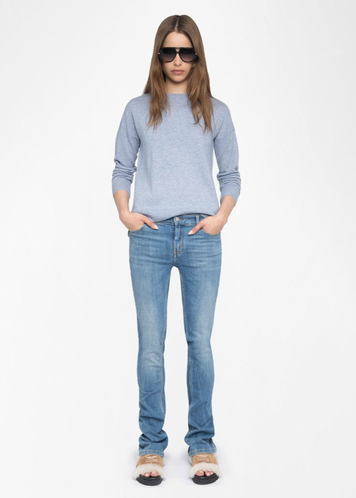 Woman wearing a light blue sweater and jeans on a white background