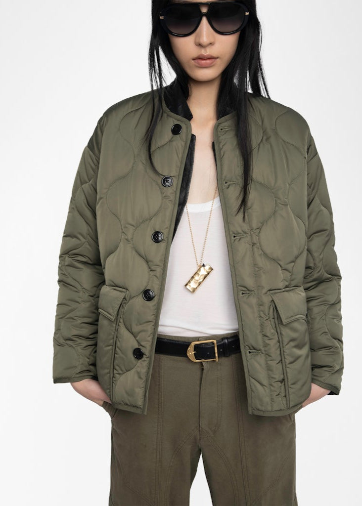 Person wearing a green quilted jacket on a white background