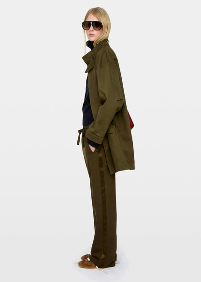 Person wearing a green trench coat and sunglasses on a white background